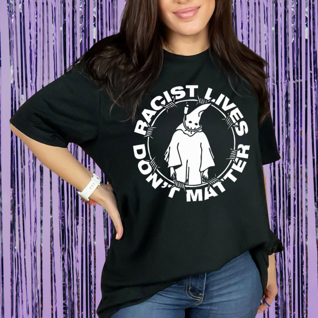 Person wearing a black t-shirt with a graphic design and text against a purple curtain background